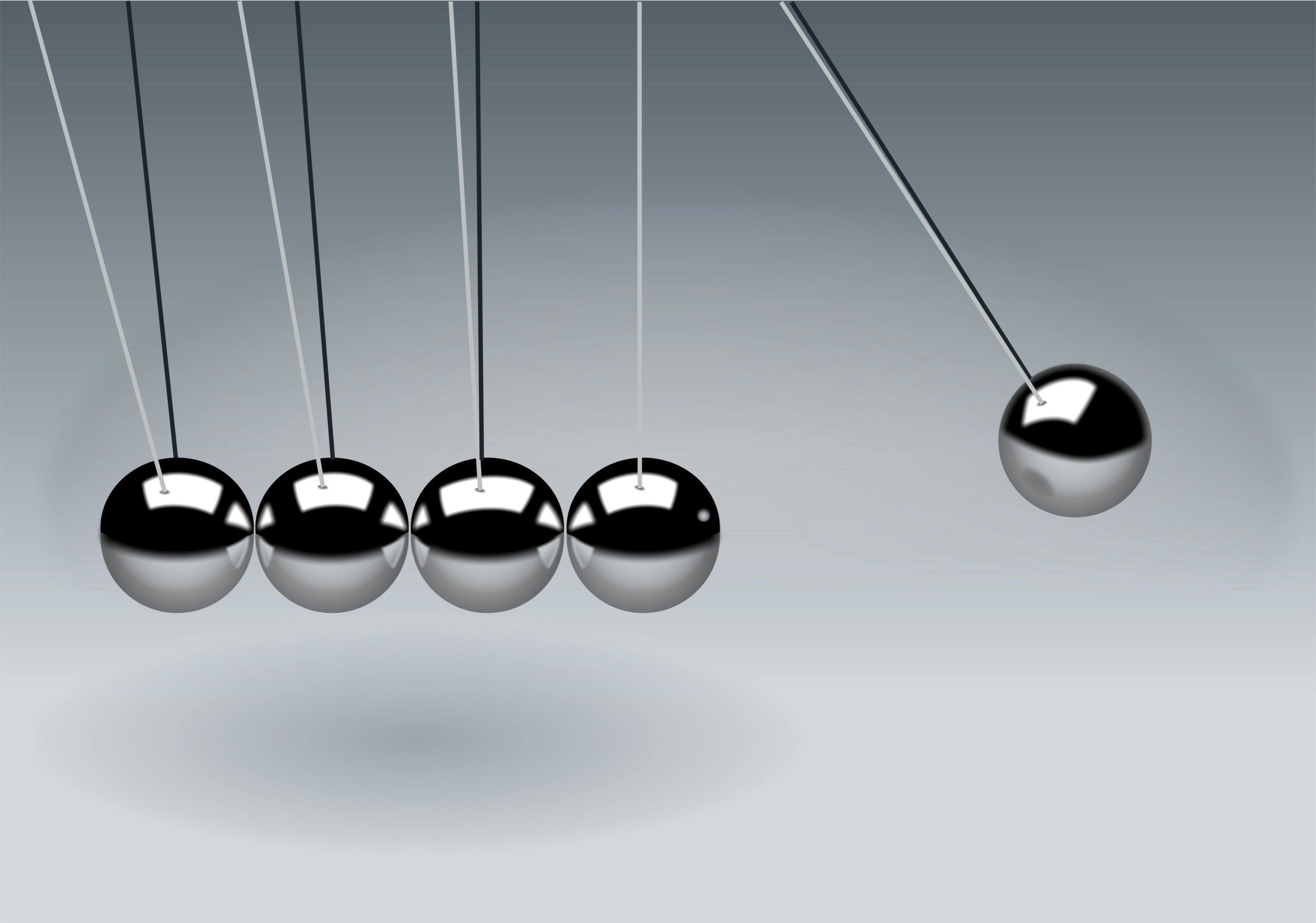 suspended row of metal balls with one having bounced off the end, symbolizing a transfer of energy