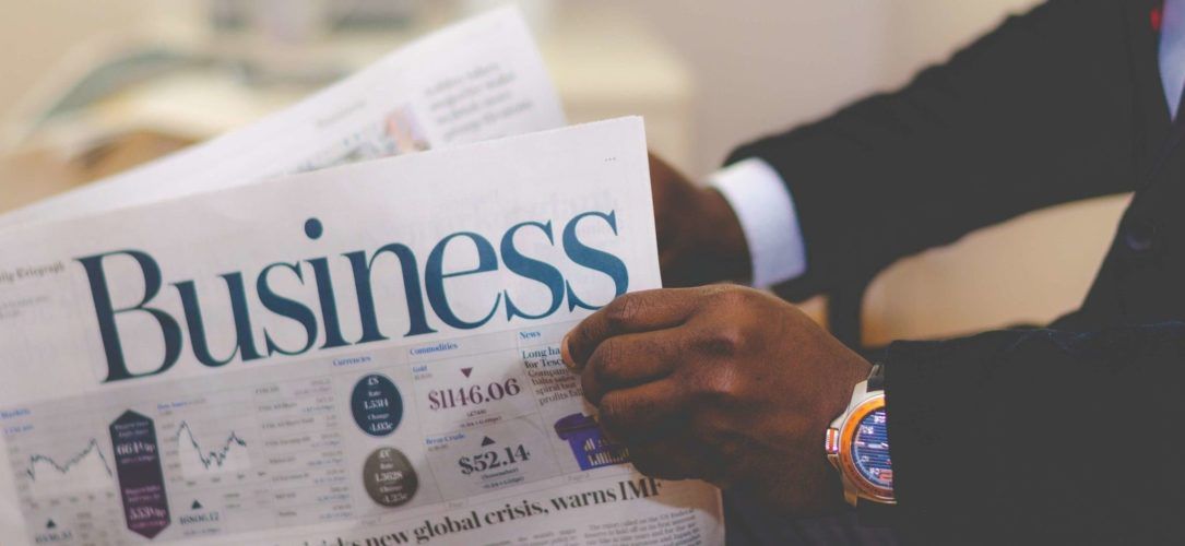 Two hands holding the business section of a newspaper