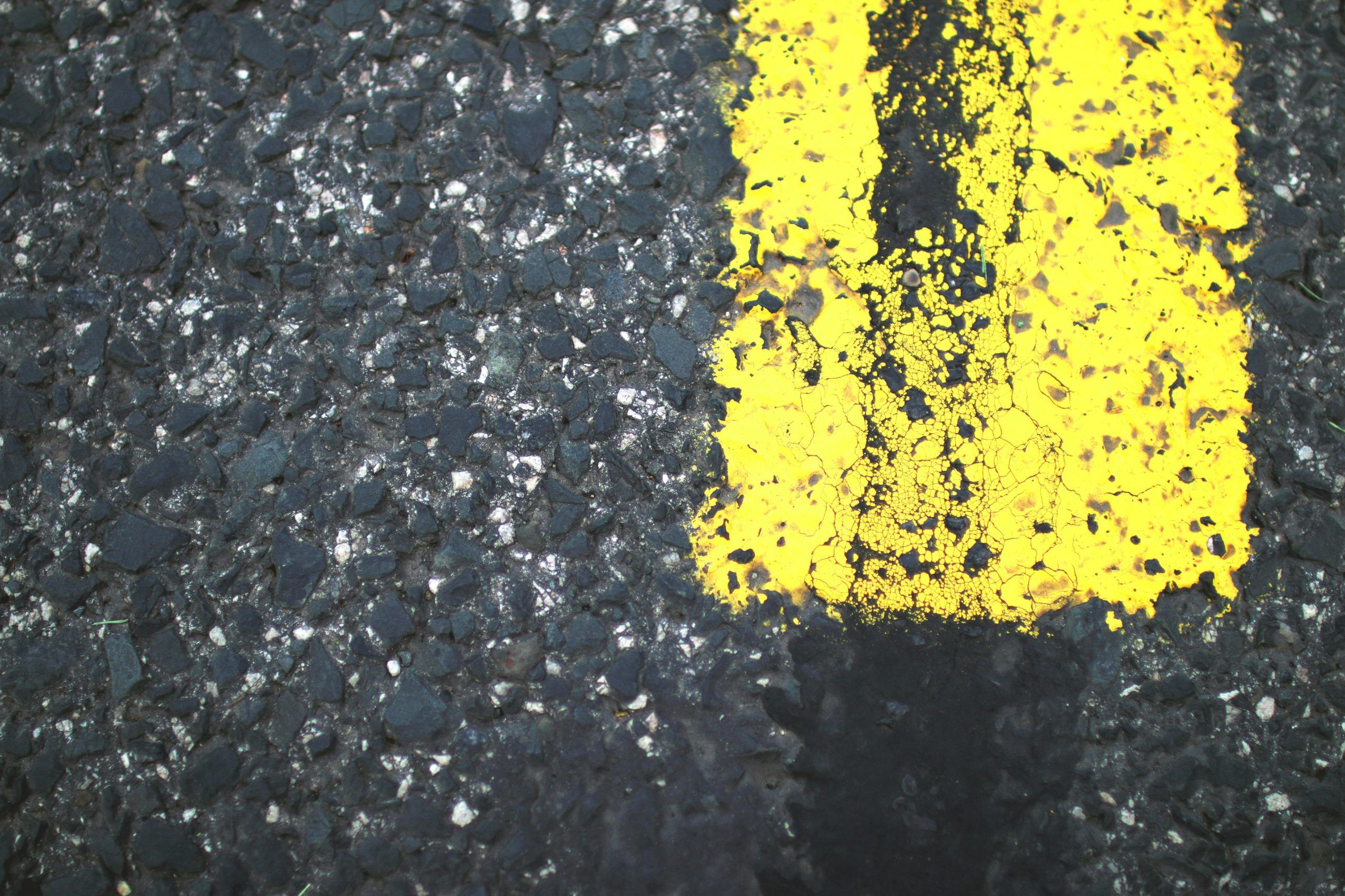 Close-up of asphalt road with part of a yellow lane marking line in view